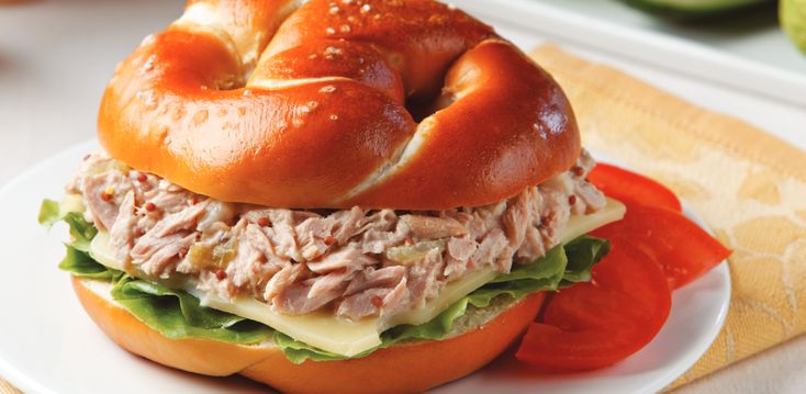 a sandwich with meat, cheese and tomato slices on it sitting on a white plate