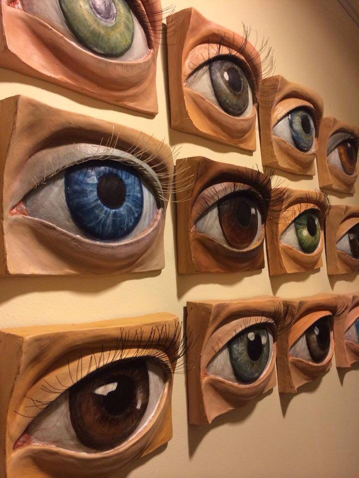 an assortment of different colored eyes displayed on a wall in front of each other, all with their own individual eyeballs