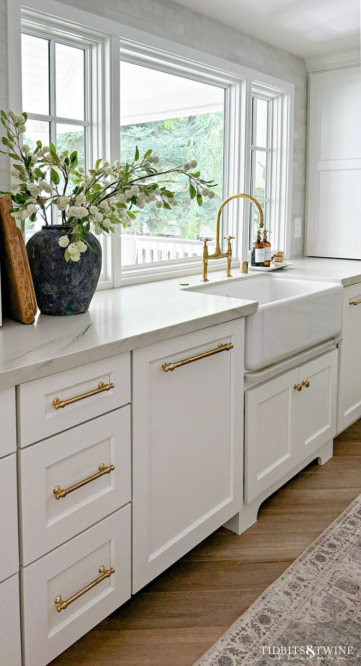 a kitchen with white cabinets and gold pulls on the handles is pictured in this image