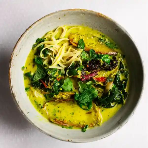 a white bowl filled with pasta and greens