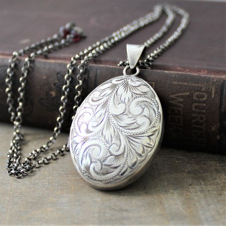 "This extra large sterling silver locket has a lovely swirling plume design etched on the front. The back of the piece, which has been engraved with the previous owners initials MEW, bears the traditional English hallmarks, made in Birmingham England in 1977. Opening reveals two spaces in which to place your beloved photographs.. The pendant is set on a new long sterling silver chain which has been antiqued to a rich charcoal gray. The chain has a little surprise at the end, tiny garnet stones f Vintage Carved White Gold Jewelry, Ornate Silver Jewelry With Engraving Option, Vintage Silver Carved Jewelry, Vintage White Gold Jewelry With Engraving Option, Vintage Carved Silver Jewelry, Ornate White Engraved Necklace, Victorian Silver Jewelry With Engraving Option, Silver Filigree Jewelry For Keepsake, Vintage Silver Carved Necklaces