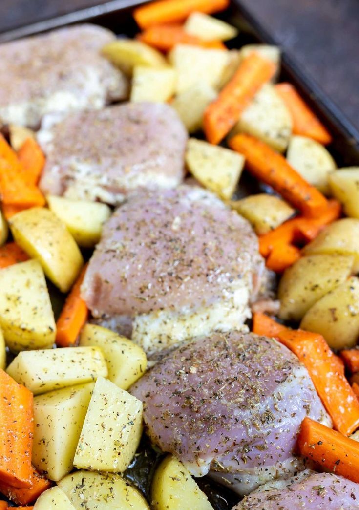 chicken, potatoes and carrots in a baking pan with seasoning on top for garnish