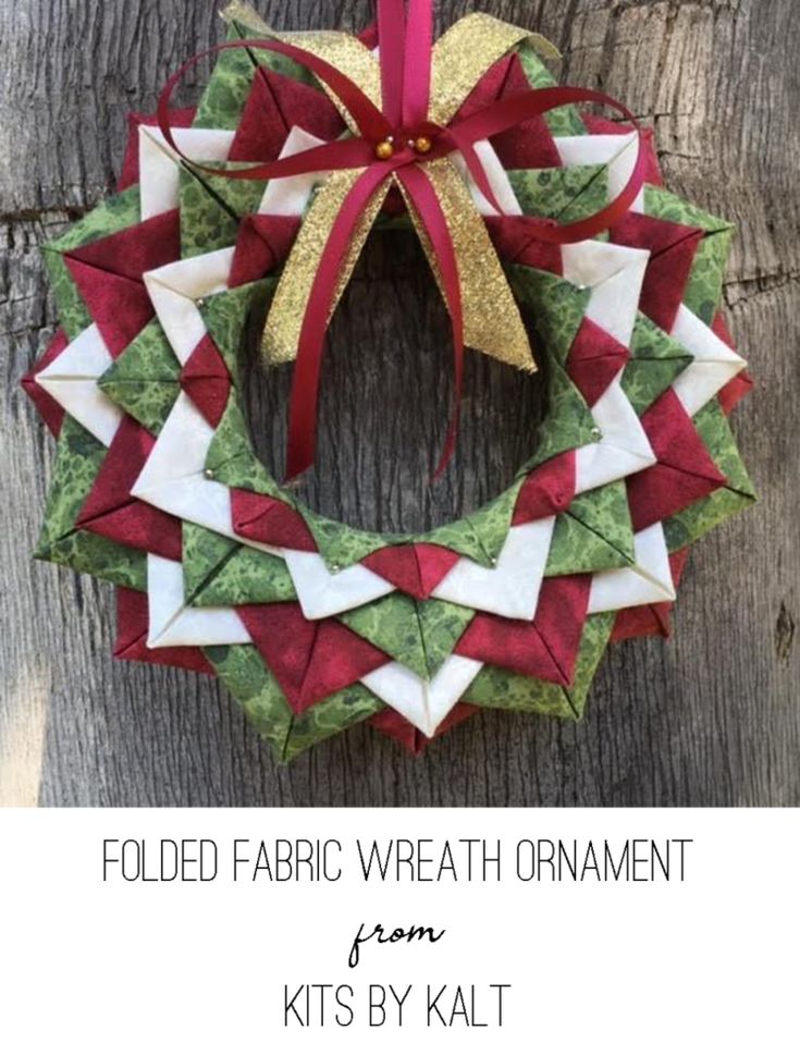 an origami wreath hanging on the side of a wooden fence with a red ribbon