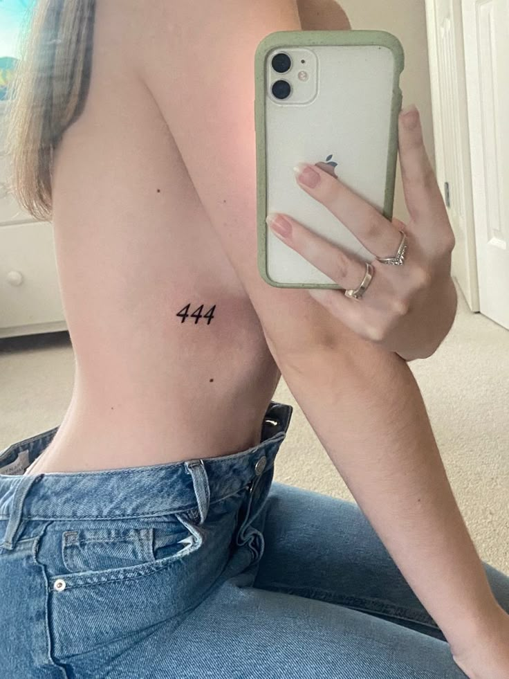 a woman is sitting on the floor with her phone in her hand and showing off her tattoos