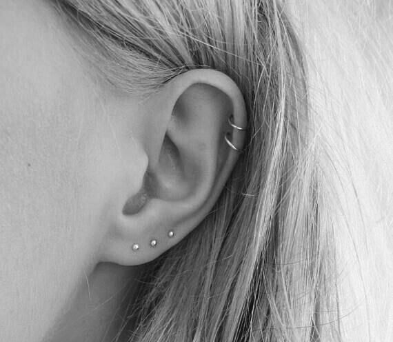 black and white photograph of a woman's ear with two piercings on it