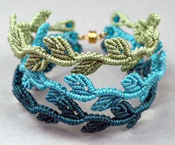 a close up of a bracelet with beads and leaves on the front, in blue and green colors