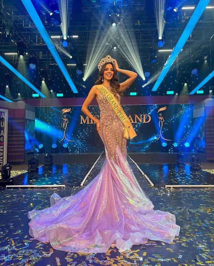 a woman in a gown on stage with confetti around her waist and crown