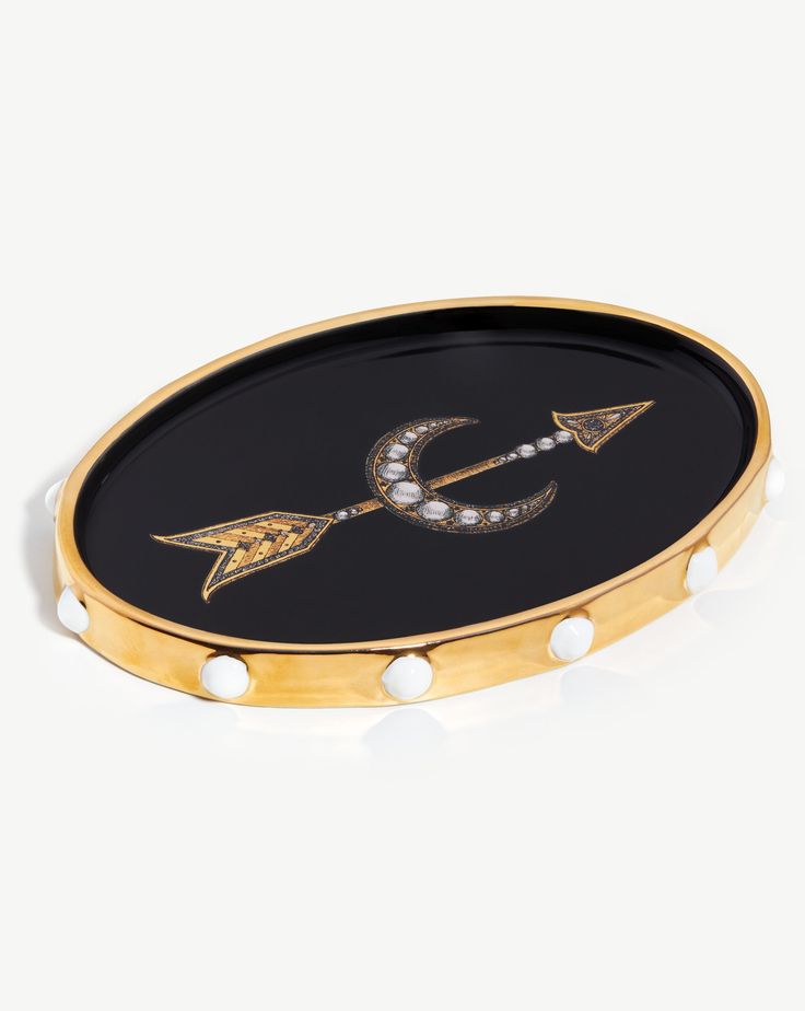 a black and gold tray with an arrow on the bottom, decorated with pearls and diamonds