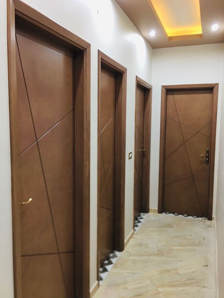 an empty hallway with three brown doors