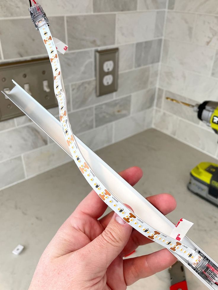 a person holding some tape in their hand near a sink with tools on the counter