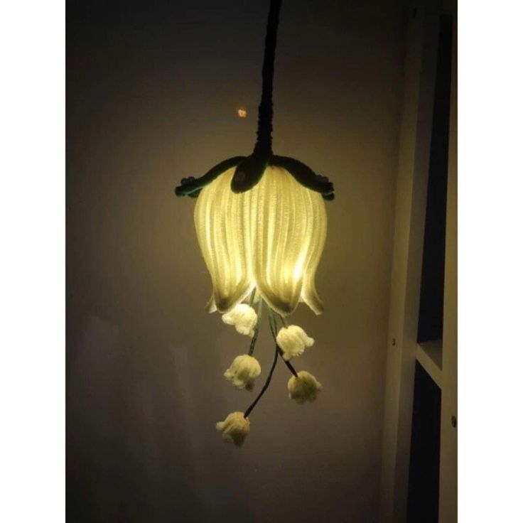 a light that is hanging from the ceiling with flowers on it's head and some lights in the background