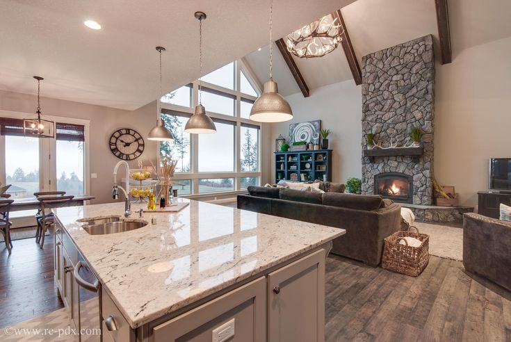 a large kitchen with an island in front of a living room and dining room area