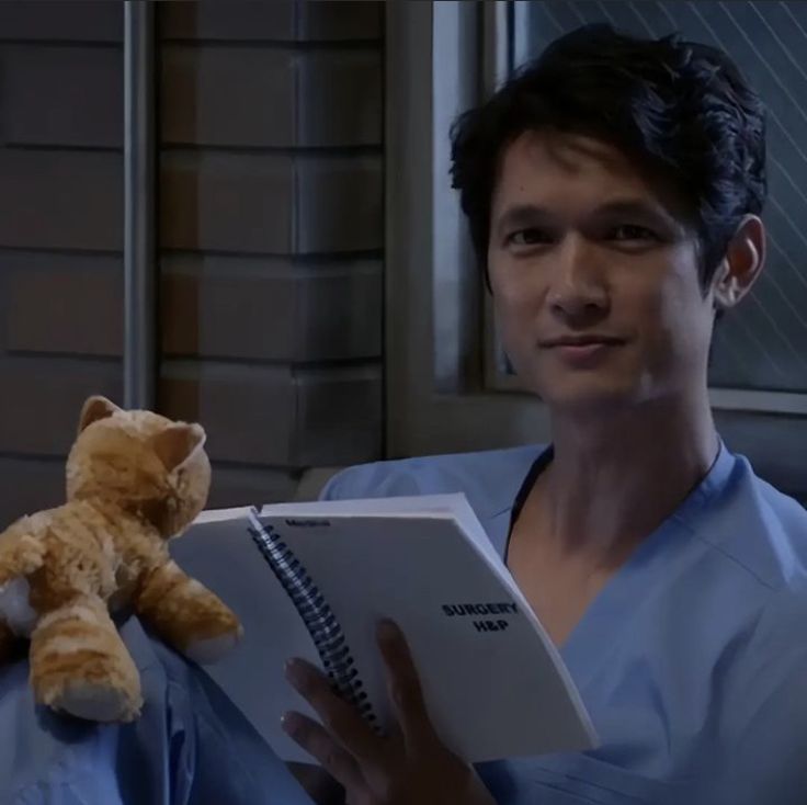 a man in scrubs holding a book and a teddy bear