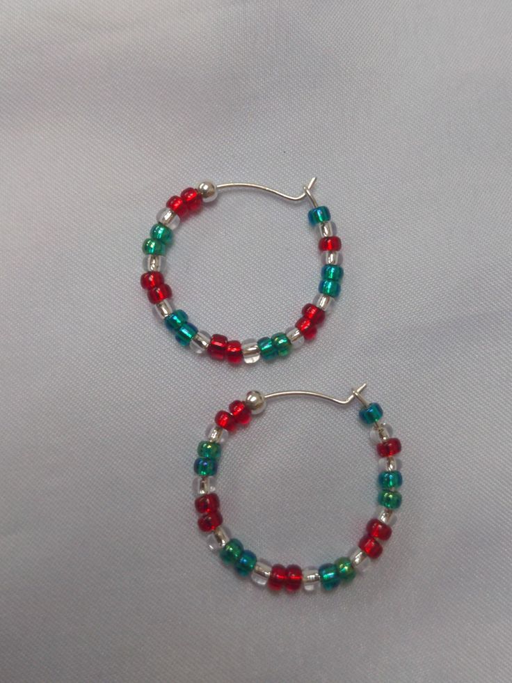 A pair of red, silver lined and green glass seed bead earrings, with a silver 'stopper bead' at the end to stop them easily slipping off the silver hoop.  The hoop has a diameter of approx. 2.3cm. these are quite delicate hoops so care must be taken when putting in and taking out. A fun, festive pair of unique, handmade earrings, with a Christmassy style, ideal for the festive time of year. I can also make in alternative colour combinations if needed, just send me a message with your requirements! To keep your jewellery in the best condition for the longest period, please note:  - Remove jewellery before bathing, showering or swimming.  - Avoid direct contact with body lotions, perfumes and any other chemicals. - Remove jewellery before sleeping. - When not in use, store jewellery in it's Colorful Beads Christmas Earrings Gift, Festive Nickel-free Hoop Earrings, Colorful Beads Earrings For Christmas Gift, Christmas Gift Earrings With Colorful Beads, Nickel-free Hoop Earrings For Festive Occasions, Nickel-free Hoop Earrings For Festivals, Red Christmas Jewelry With Colorful Beads, Colorful Beaded Jewelry For Holiday Gifts, Holiday Jewelry Gift With Colorful Beads