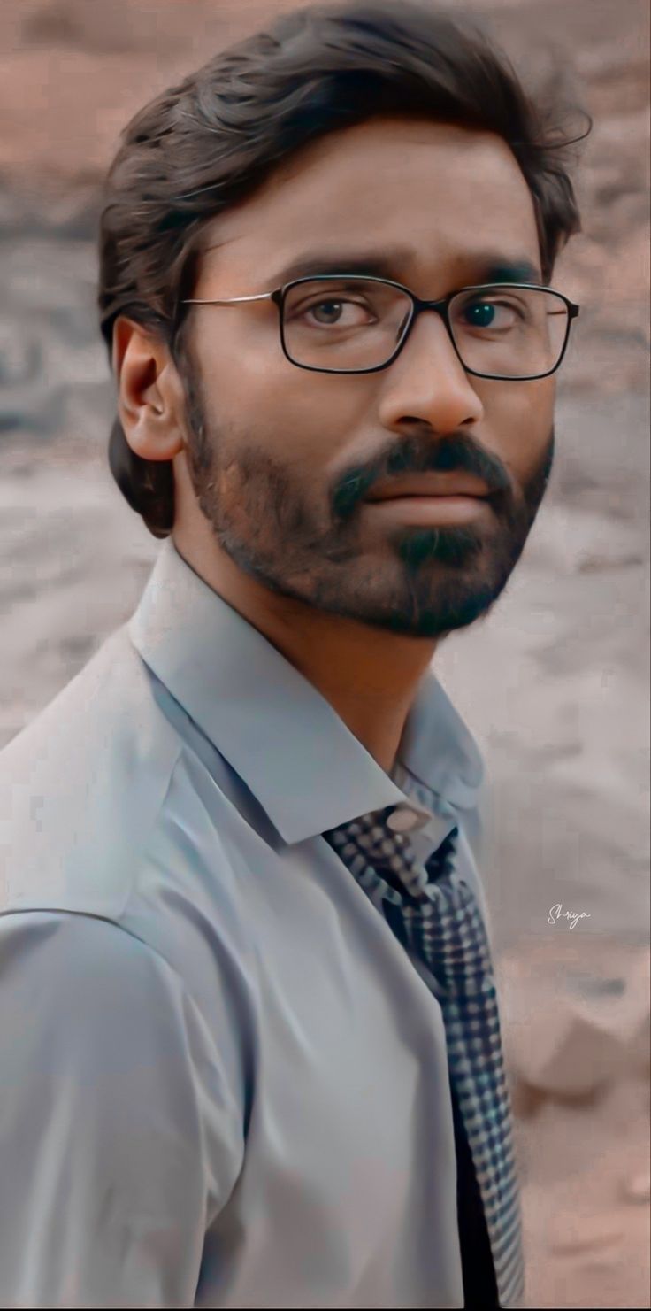 a man with glasses and a beard wearing a shirt and tie in front of water