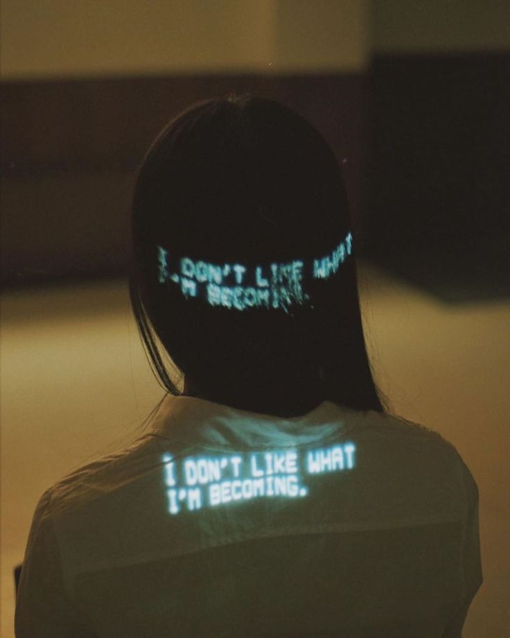 a woman with her back turned to the camera, wearing a white shirt that says i don't like what she is doing