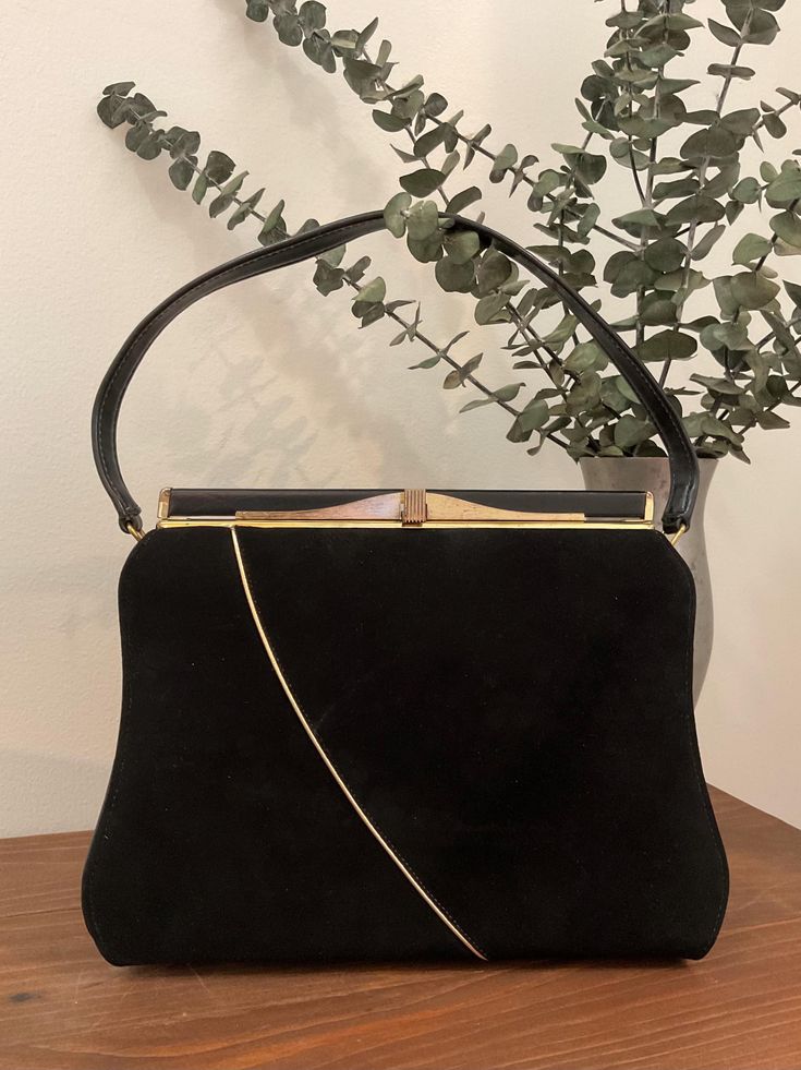 1960s A Life Stride Black Top Handle Handbag, Vintage Black Suede/Vinyl Purse, Vintage Accessory  Stunning 1960s black suede and black vinyl top handle handbag made by a life stride handbag. The front body of the handbag is black suede with a gold decorative strip running down the front and onto the bottom of the bag. Both sides and back of the bag are black vinyl. It features a black single vinyl handle strap. There is gold tone metal hardware with a thumb lift closure that works well and closes tightly. Opens to a black faille lining with one open pocket behind a nylon zippered pocket. Attached a life stride handbag label. Stamped 84005 820Z42. Protective feet are on the bottom of the bag. Beautiful vintage condition *the front exterior is immaculate.  The back exterior has some surface Mid-century Rectangular Party Bags, Vintage Black Bag For Vintage Events, Vintage Evening Shoulder Bag With Gold-tone Hardware, Vintage Evening Bag With Detachable Strap And Top Handle, Black Vintage Bags For Vintage Events, Black Rectangular Bag For Vintage Fashion, Vintage Top Handle Evening Bag For Formal Occasions, Vintage Formal Evening Bag With Top Handle, Vintage Black Rectangular Shoulder Bag