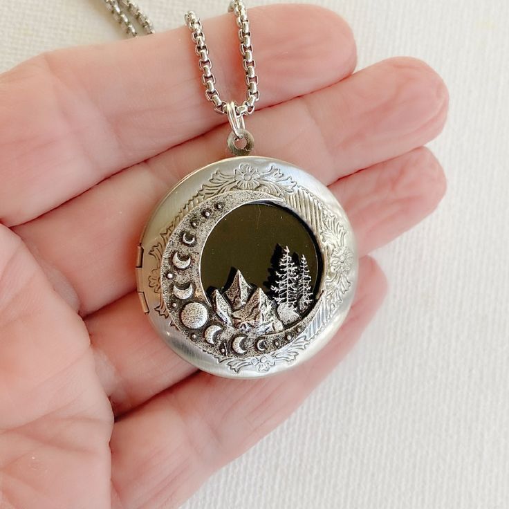 "This lovely brushed silver locket features the phases of the moon with a beautiful mountain landscape. It will become a wonderful addition to any jewelry collection. The locket is 32mm in diameter, silver plated brass and opens for a secret place to keep pictures, messages, or whatever you like. This locket can hold two 25mm inserts (about one inch.) I will include a paper template inside your locket for easy tracing. The locket has an antiqued silver stainless steel 2mm rolo style chain with a Etched Pendant Locket Necklace As A Gift, Nature-inspired Etched Jewelry For Gifts, Nature-inspired Etched Jewelry Gift, Pendant Locket Necklace With Engraving Option For Gifts, Gift Locket Pendant Necklace With Engraving Option, Engraved Pendant Locket Necklace As Gift, Engraving Option Pendant Locket Necklace For Gift, Bohemian Engraved Round Locket Necklace, Engraved Round Pendant Jewelry For Personal Use