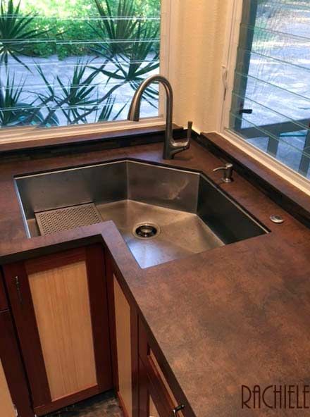 a kitchen sink and counter in front of a window