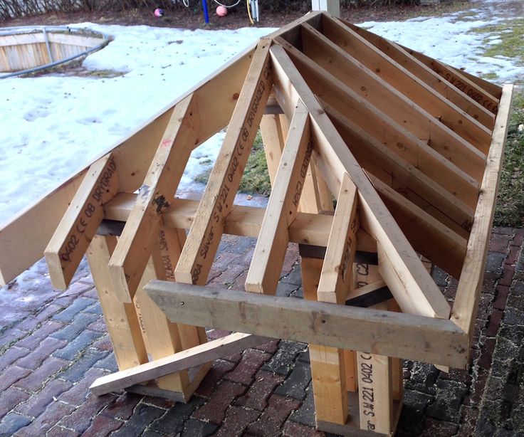 a wooden structure sitting on top of a brick floor next to a yard filled with snow