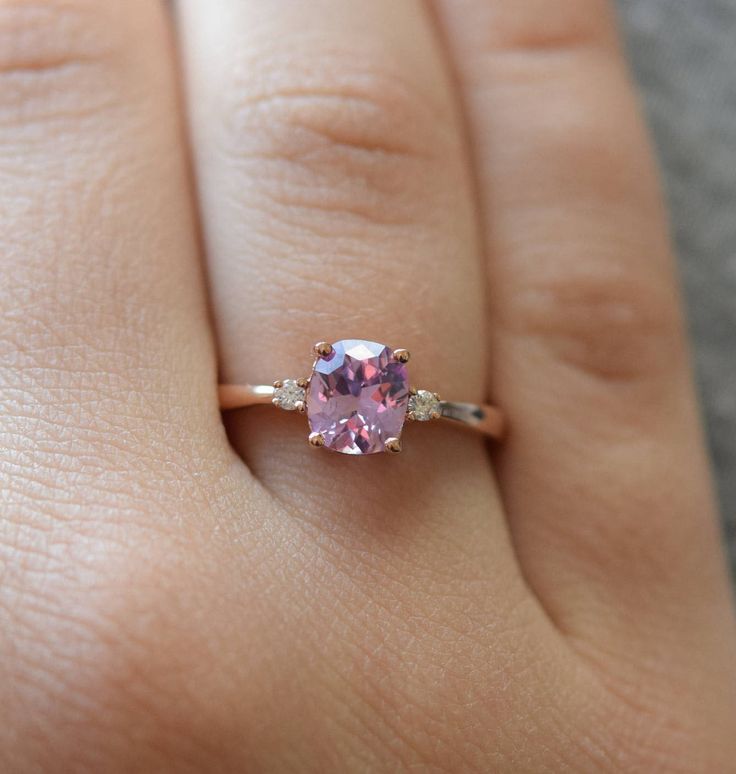 a woman's hand with a pink and white ring on her left hand, showing the center stone