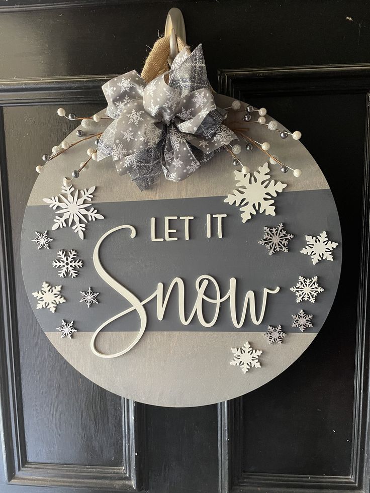 a sign that says let it snow hanging on a door with a bow and ribbon