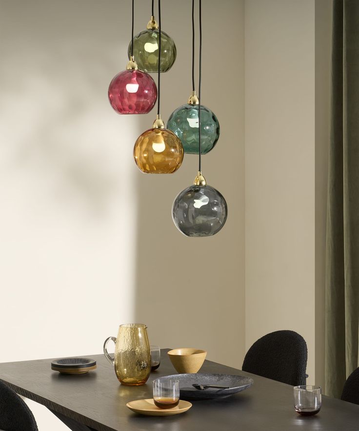 a dining room table with four hanging glass orbs