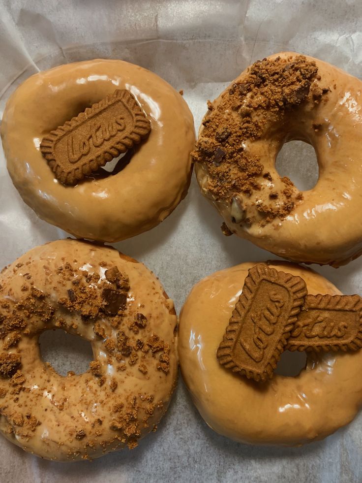 four doughnuts with frosting and cookies on them sitting in a wrapper