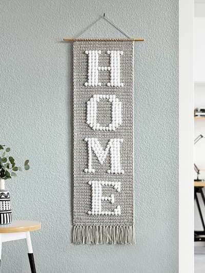 a wall hanging with the word home on it and a table in front of it