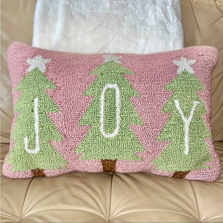 a pink and green christmas tree pillow sitting on top of a couch