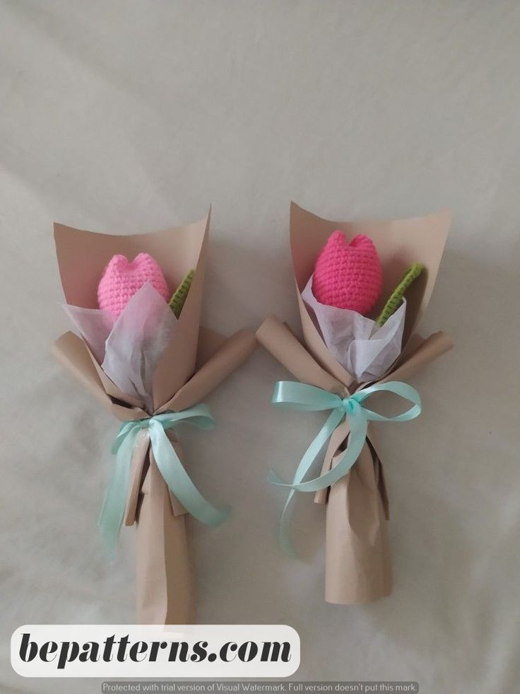 two pink flowers wrapped in brown paper with green ribbons