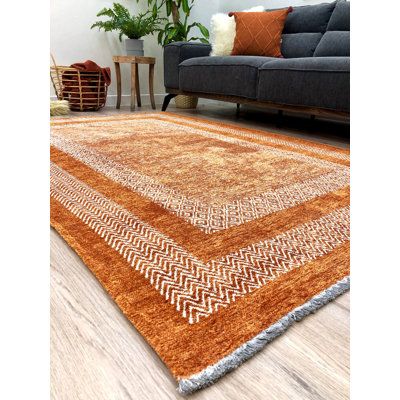 an orange and white area rug in the middle of a living room with a couch