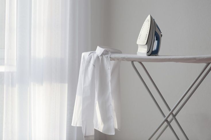 an ironing board next to a white curtain