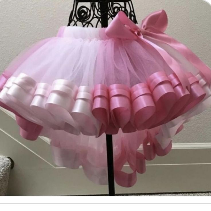 pink and white tulle skirt with bows on the bottom, attached to a metal stand