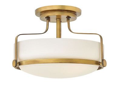 a semi - flush ceiling light with white glass shades in an antique brass finish fixture