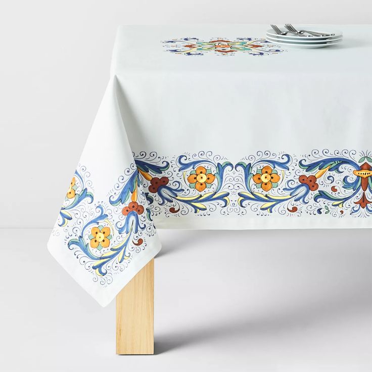 a white table cloth with blue and orange designs on it, next to a fork and knife