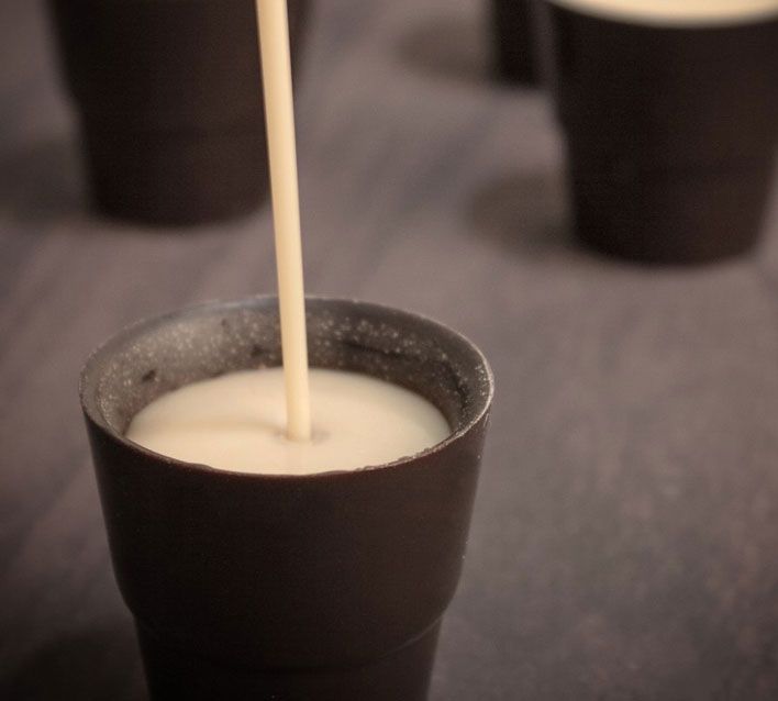 there are cups with milk being poured into them and the straw sticking out of one cup