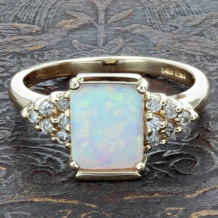 Vintage 14k Yellow Gold Opal And Diamond Birthstone Anniversary / Cocktail Ring This Beautiful Cocktail Ring Is Made Of 14 Karat Yellow Gold And Features A Gorgeous Rectangular Opal Gemstone That Gleams With Rainbow Colors In The Light. The Opal Is Accented With Multiple Round-Cut Diamonds At Its Sides, Finalizing The Gorgeous Design. "14k" & An "Ema" Maker's Mark Are Stamped Onto The Inside Part Of The Band. Ring Size: 6.5 (Resizable) // 1.7-2mm Band Width Metal: 14 Karat Yellow Gold Weight: 2.33 Dwt // 3.62 Grams Gemstone: 1 Opal (8.5mm X 7mm Width) Diamonds: 6-Round (.25 Carat Total) 777458-1 * Av212 Art Deco Diamond Rings, Diamond Birthstone, Art Deco Diamond, Maker's Mark, Gorgeous Design, Opal Gemstone, Cocktail Ring, Round Cut Diamond, Womens Jewelry Rings