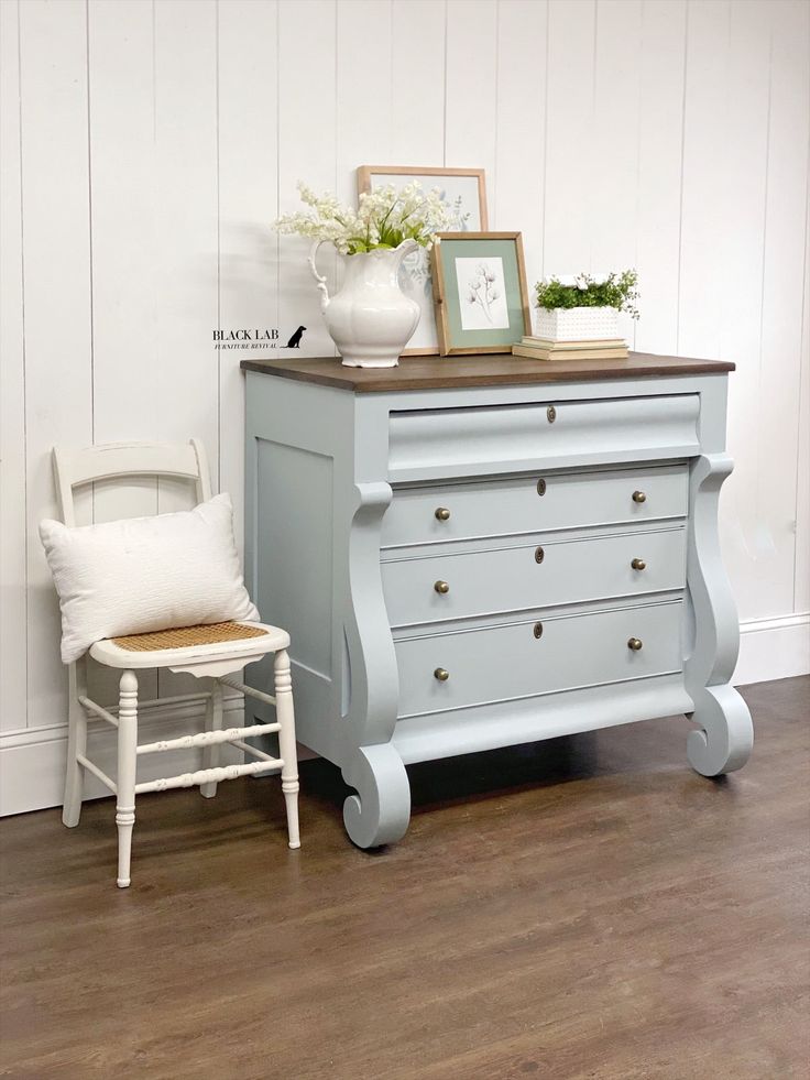 a white chair sitting next to a blue dresser on top of a hard wood floor