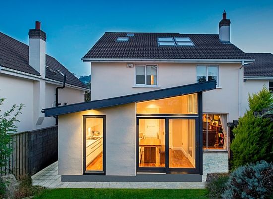 an image of a modern house with glass doors and windows in the front yard at dusk