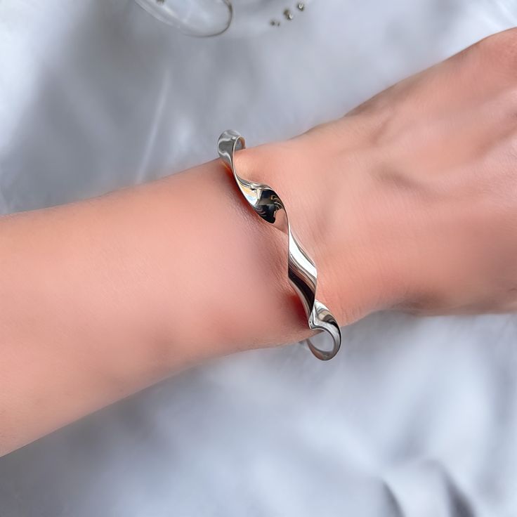 Our new unique curly bangle has a unique twist boasting a mesmerising high shine silver with kinks in its curve, like a skip in your step.  Diameter: 61 x 52 mm Top width 7 mm Weight approximately 22 grams Elegant Silver Flexible Cuff Bracelet, Silver Bracelet With Polished Finish And Modern Twist, Silver Bracelets With Polished Finish And Modern Twist, Silver Bracelets With A Modern Twist, Modern Sterling Silver Bracelet As Gift, Modern Twist Sterling Silver Bracelet, Modern Twist Sterling Silver Bangle, Modern Twist Silver Bracelets, Sterling Silver Bracelet With A Modern Twist