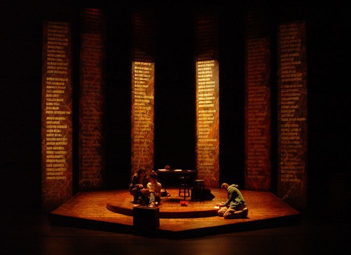 two people sitting on a stage in front of an open window with words written on it