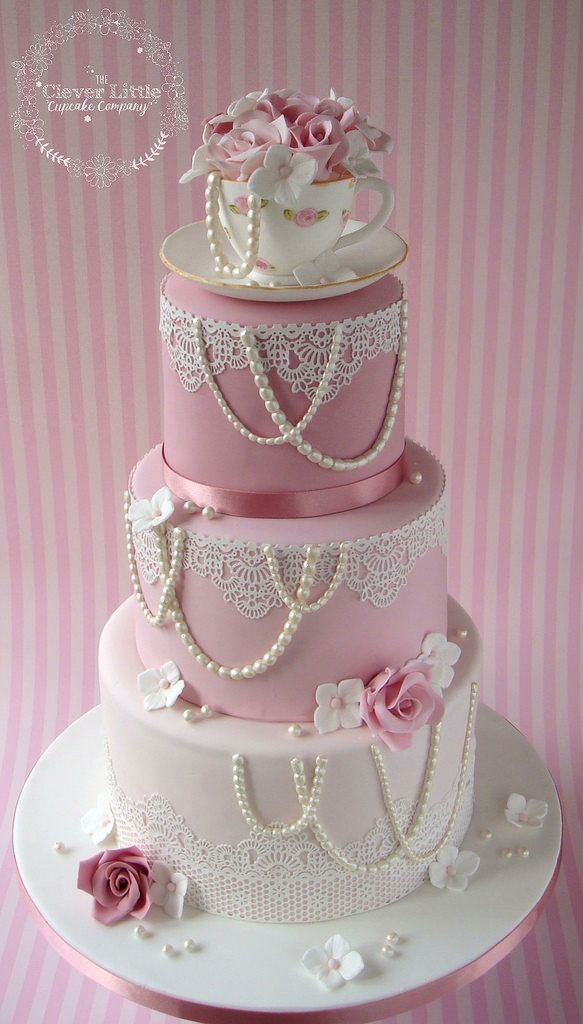 a three tiered cake with pink flowers and pearls