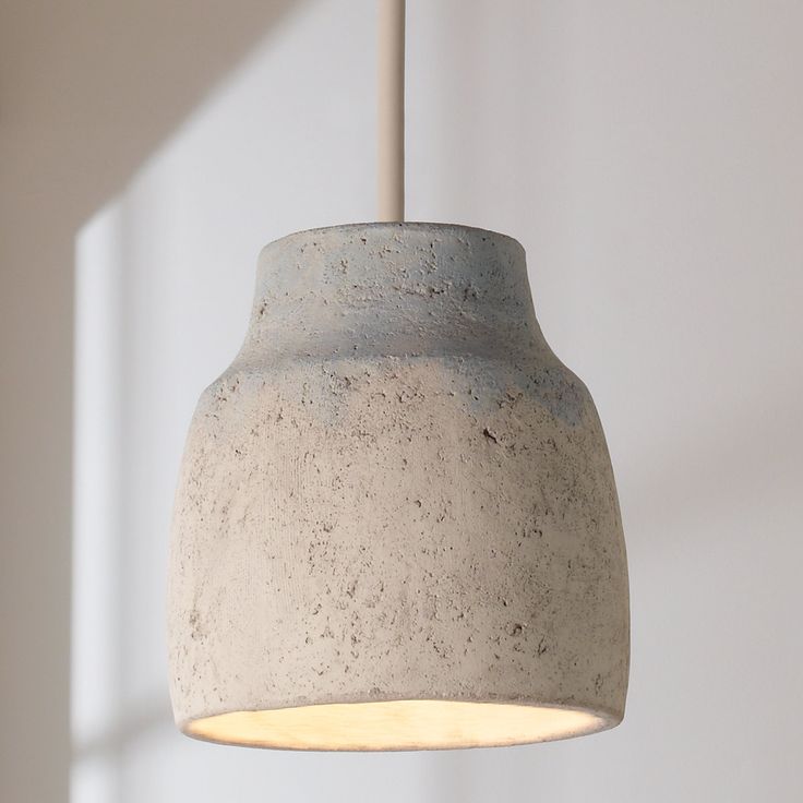 a concrete light hanging from a ceiling in a room with white walls and flooring