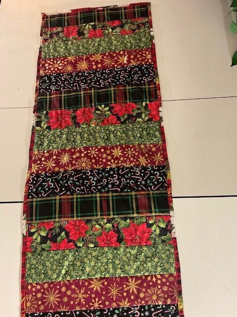 a table runner made out of fabric with flowers and leaves on the bottom, sitting on top of a white tile floor