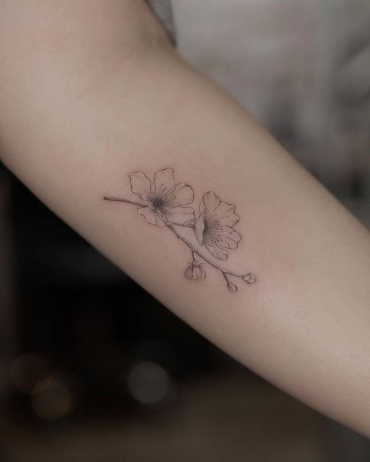 a woman's arm with a small flower tattoo on the left side of her arm