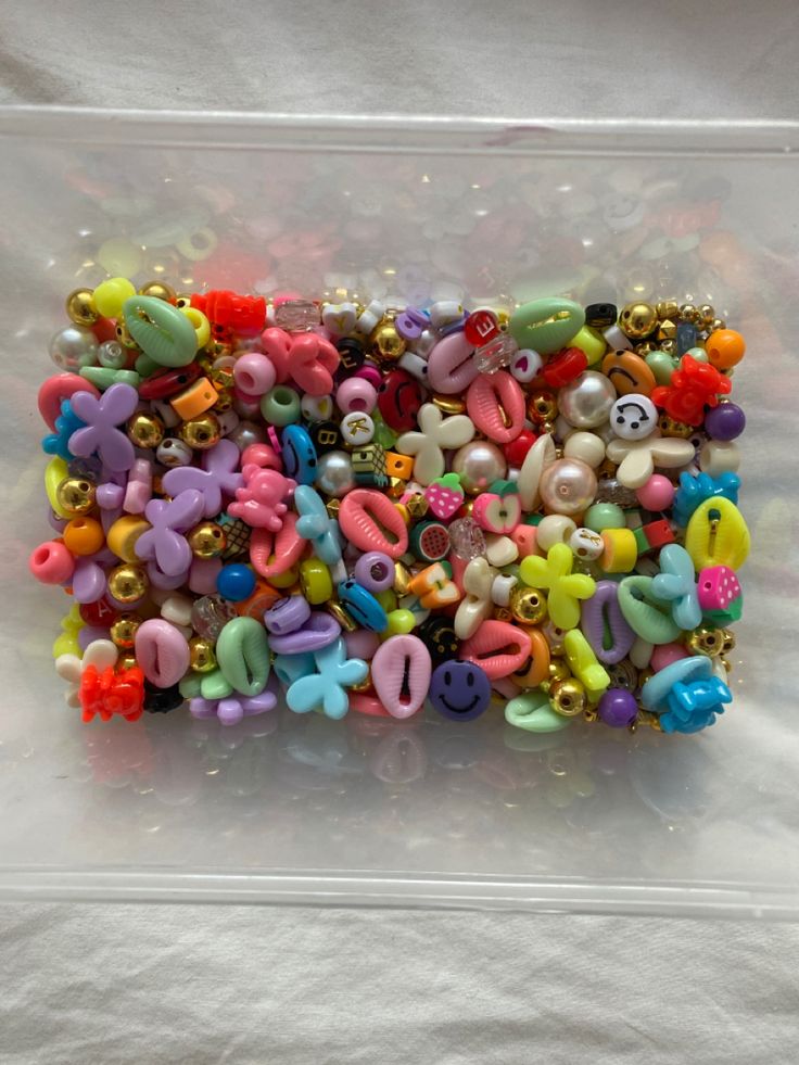 there is a plastic case with many different items in it, including beads and teddy bears