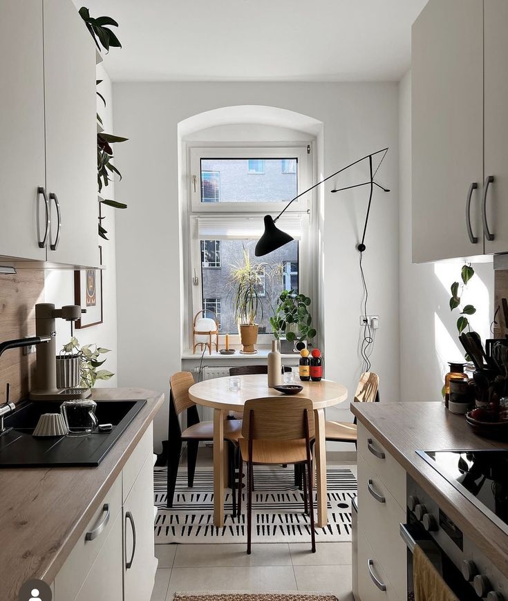 a kitchen with a table and chairs next to an open window in the middle of the room