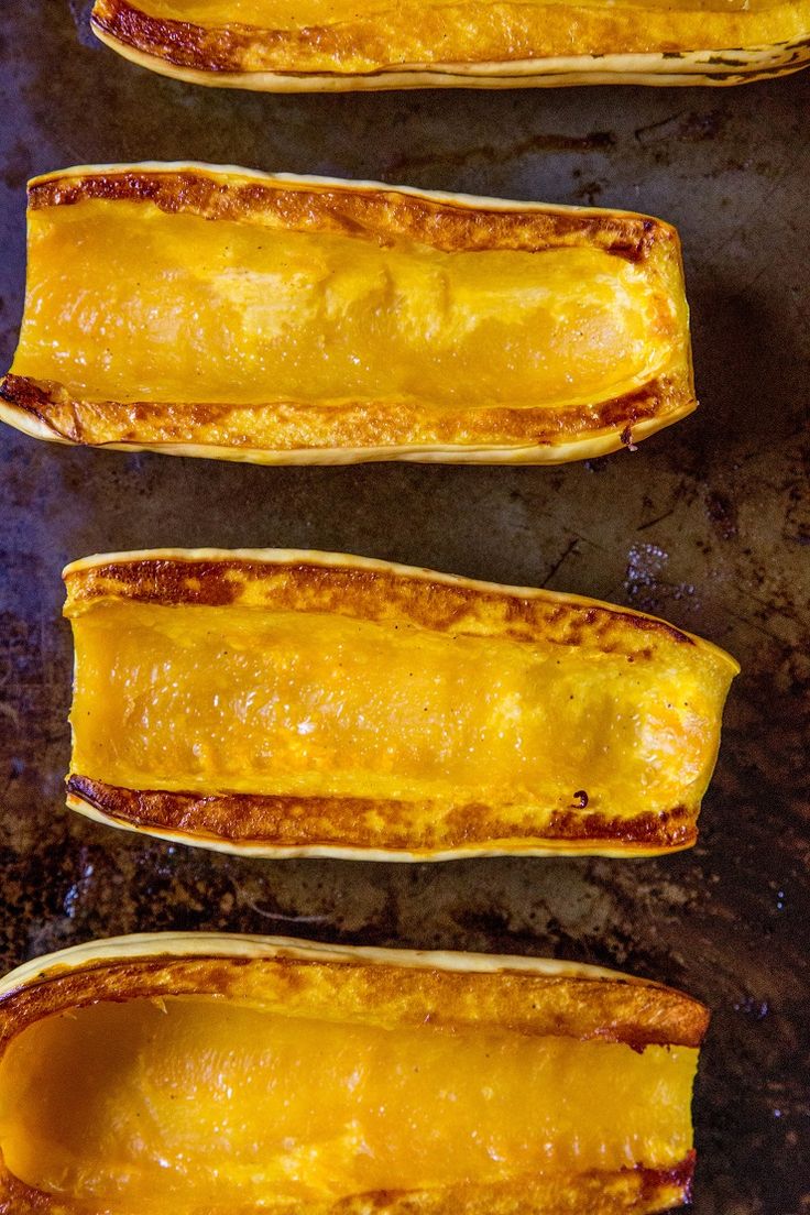 four pieces of food sitting on top of a baking pan covered in sauce and cheese