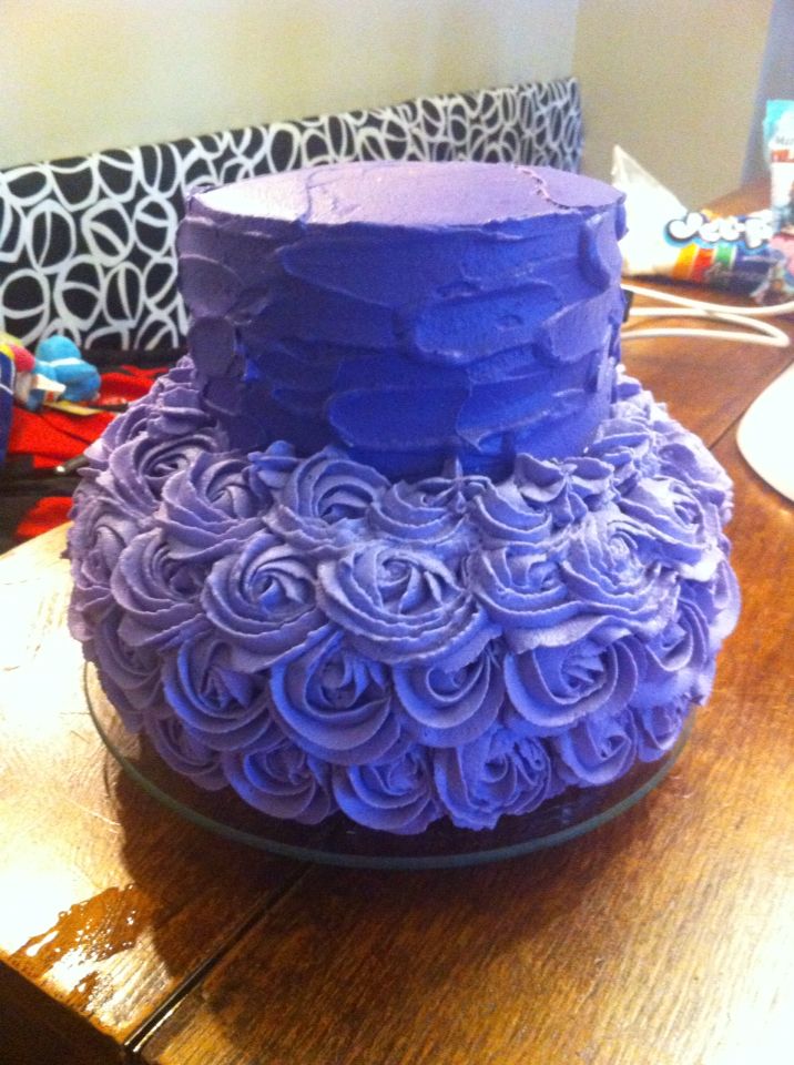 a purple cake sitting on top of a wooden table covered in frosting spirals